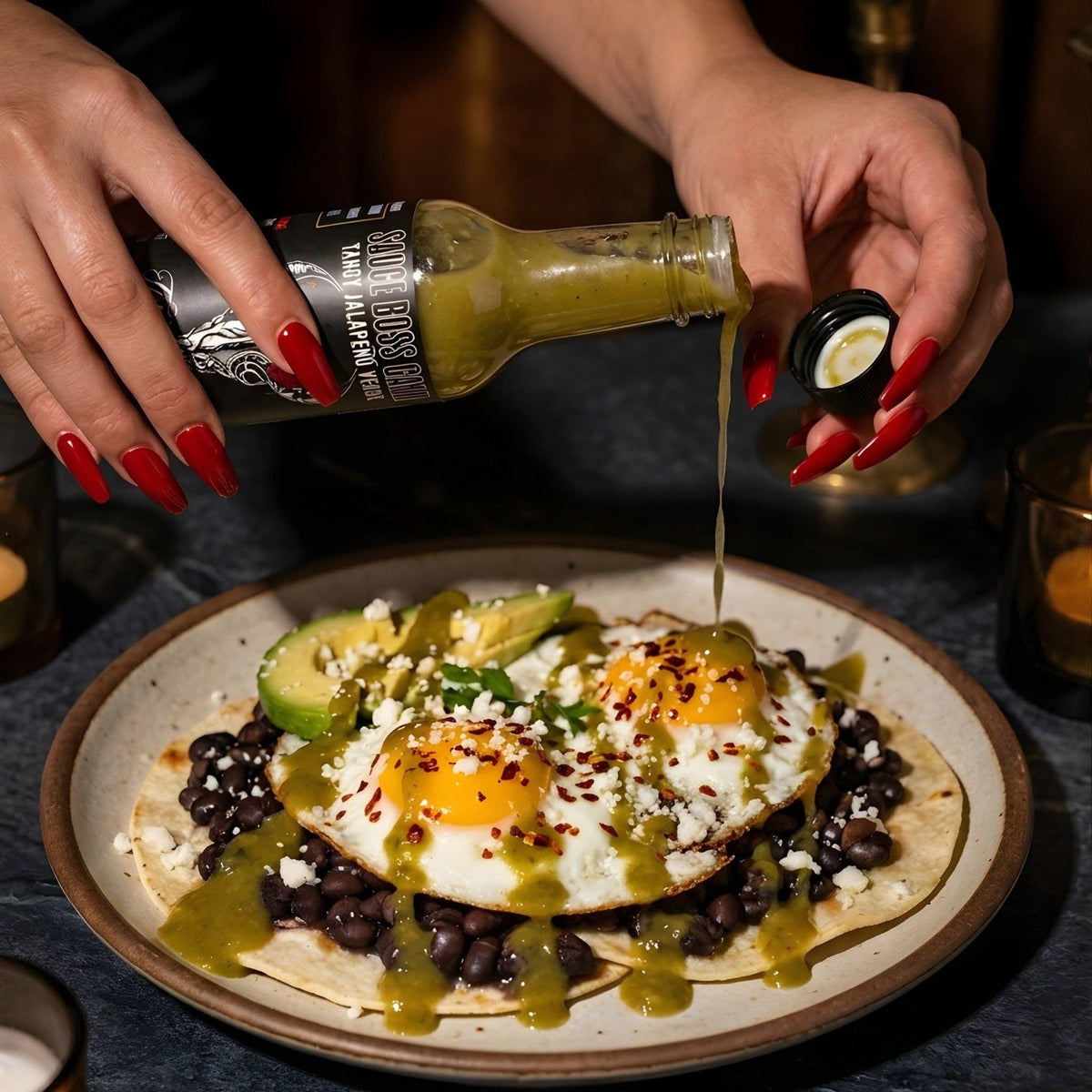 Pouring Toro Verde jalapeno hot sauce over huevos rancheros with black beans and avocado