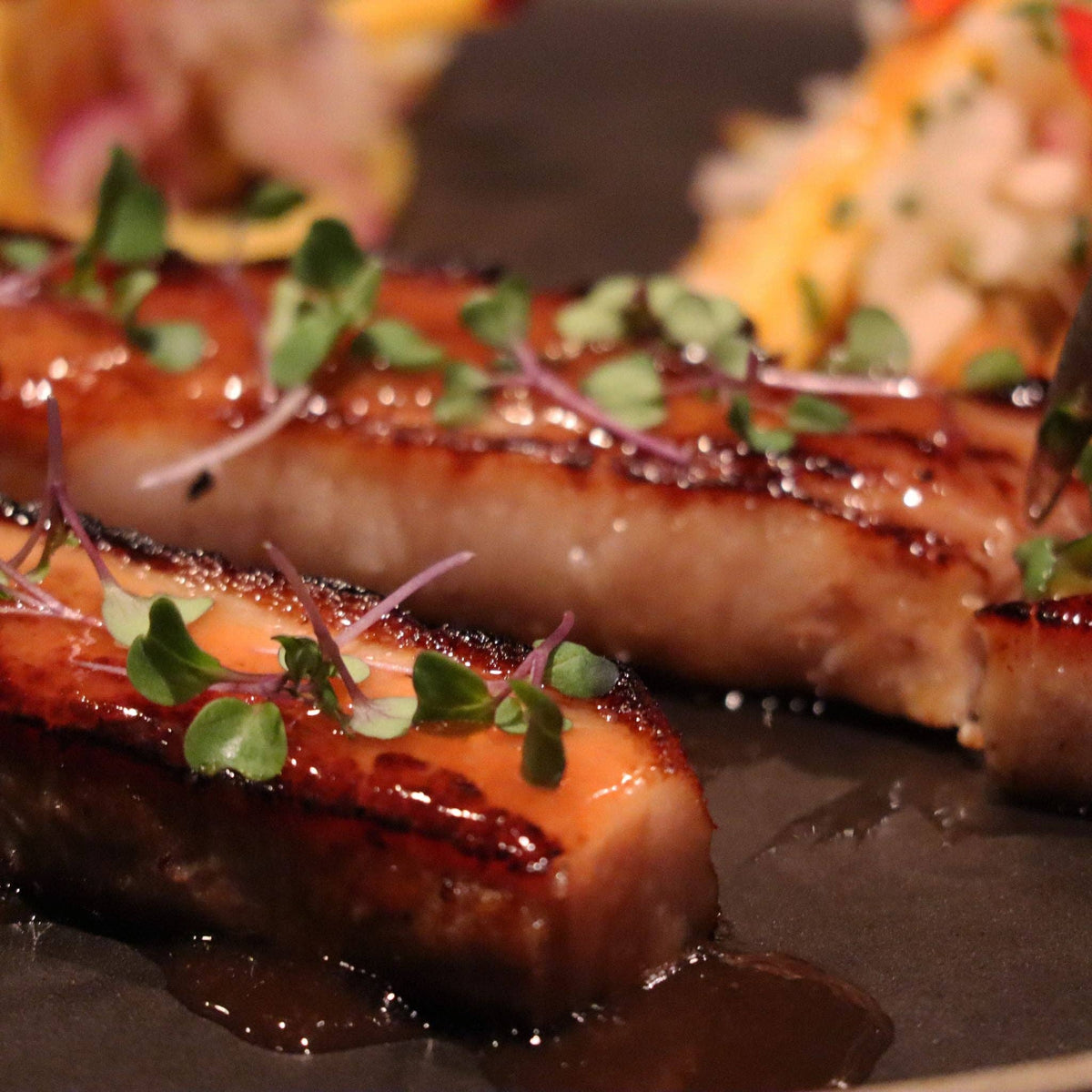 Glazed pork belly finished with Liquid Gold mango scotch bonnet hot sauce and microgreens