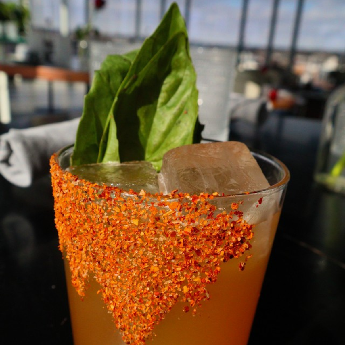 Chili-salt rimmed cocktail garnished with basil, spiced with La Jefa scorpion hot sauce