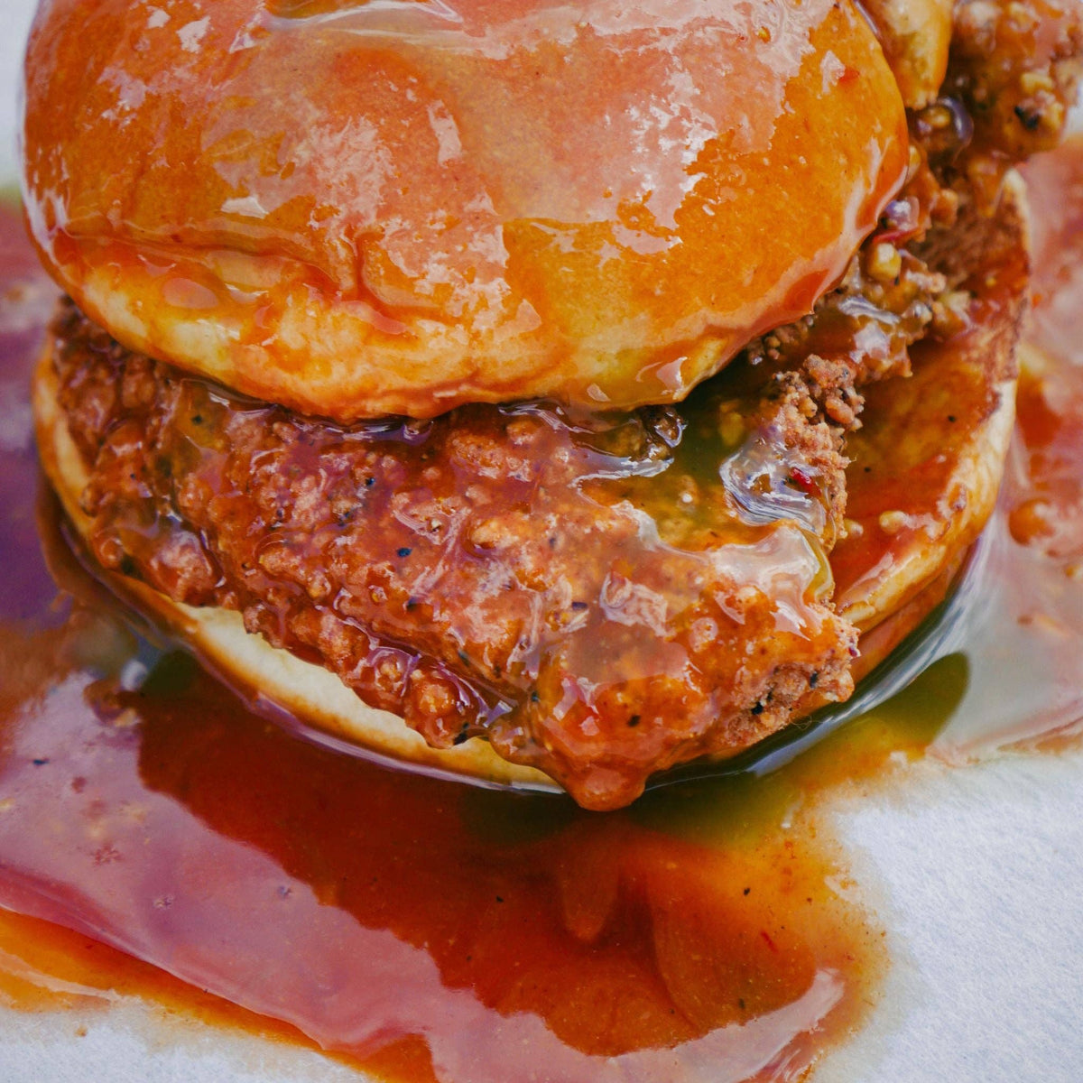 Fried chicken sandwich on a brioche bun dripping with La Jefa garlic scorpion hot sauce