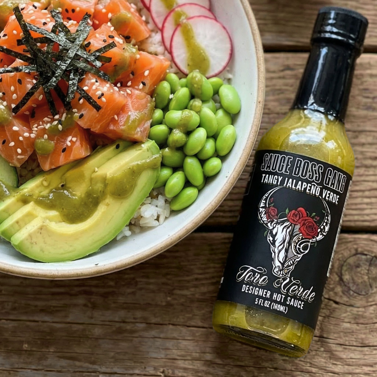 Toro Verde jalapeno hot sauce bottle next to a salmon poke bowl with avocado and edamame