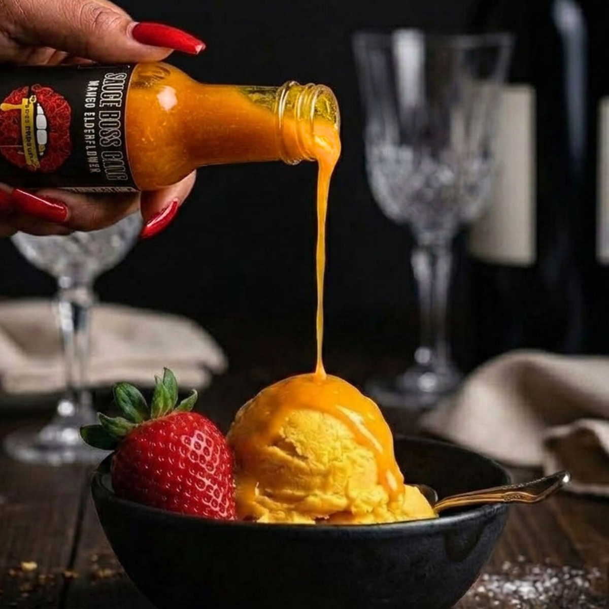 Drizzling Liquid Gold mango hot sauce over a scoop of mango sorbet with a fresh strawberry