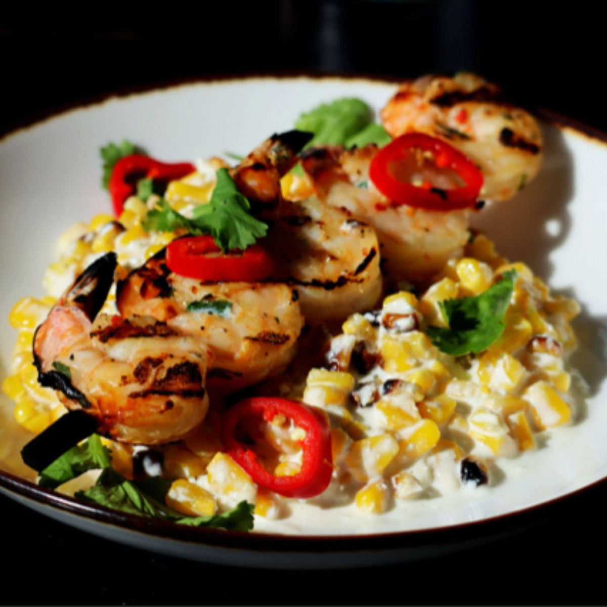 Grilled shrimp and scallops over Mexican street corn salad with sliced red chiles